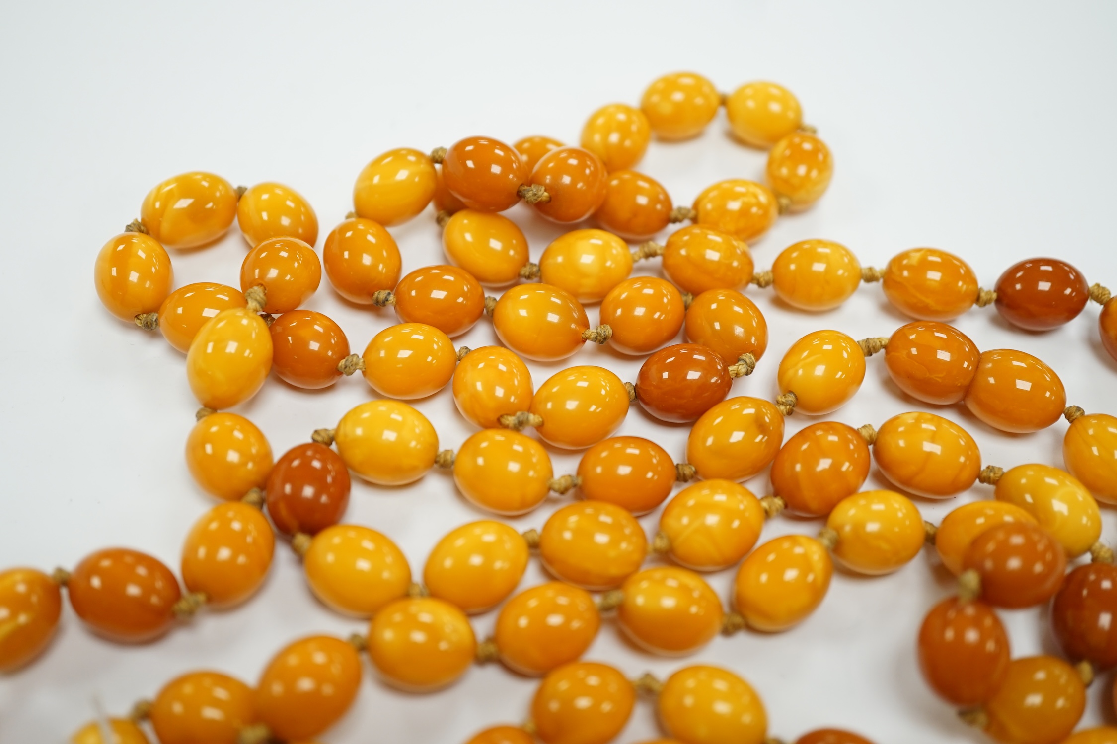 A long single strand oval amber bead necklace, 156cm, gross weight 89 grams.